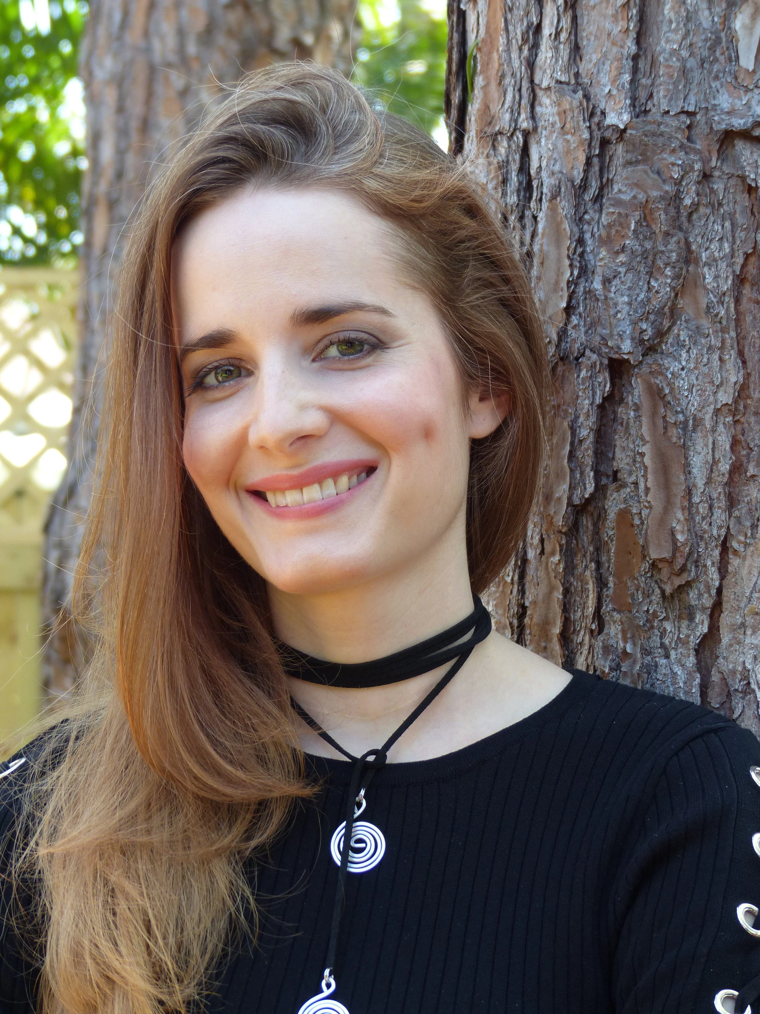 Photo of author E.G. Young smiling in front of a pine tree