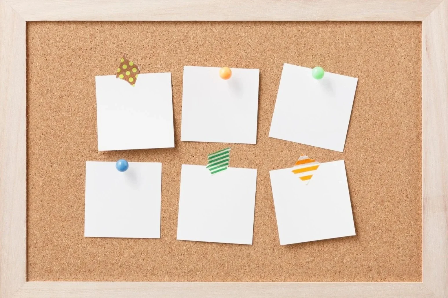 Six blank white notes pinned to a corkboard with colorful pushpins and decorative washi tape.
