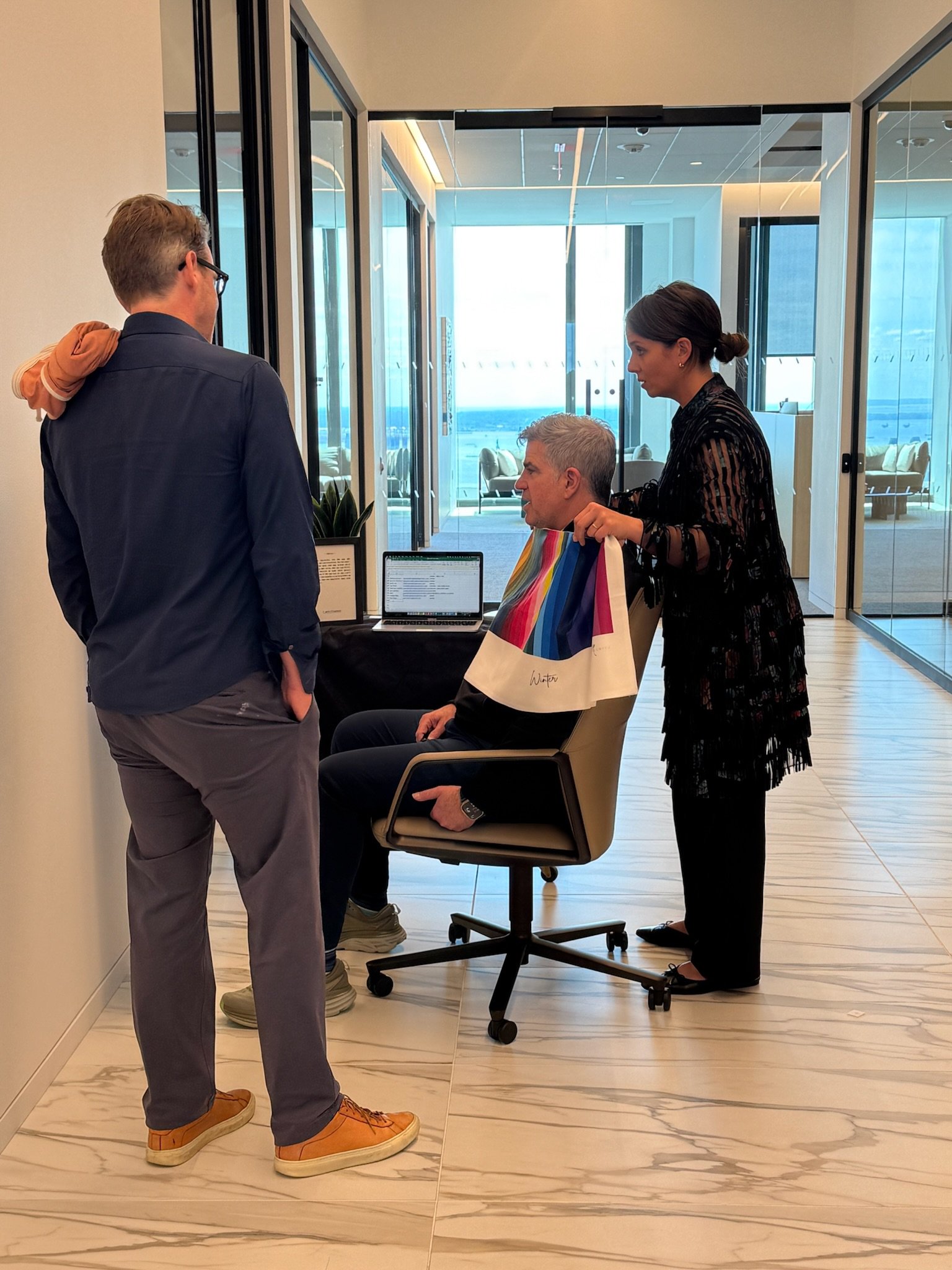 Jenna doing a corporate color consultation with a man sitting in a chair while another man nearby watches