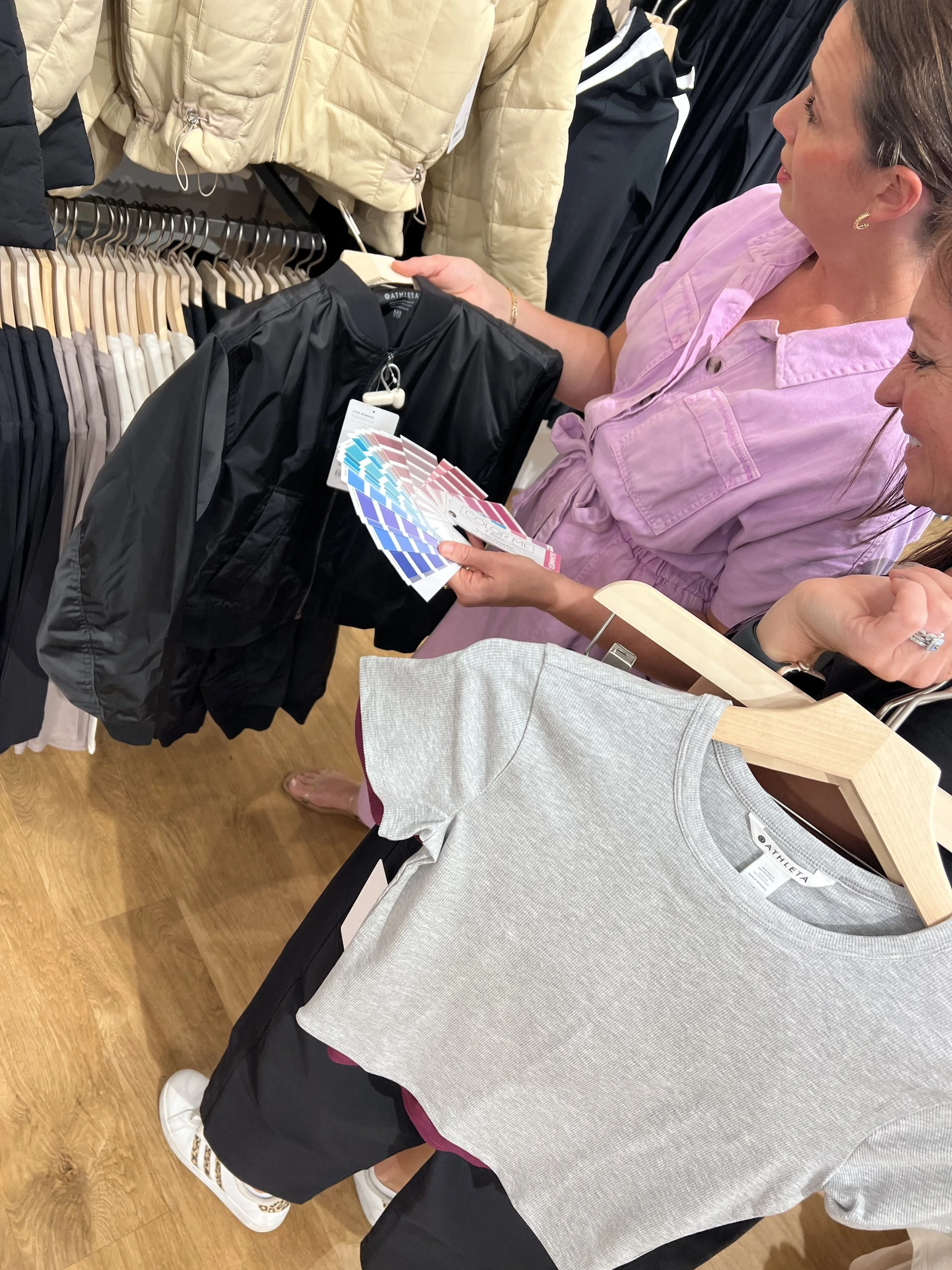 Jenna holding paper color swatches while standing next to her client in a clothing store