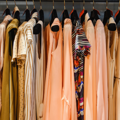 An array of yellow and peach blouses hanging on black velvet hangers in a closet