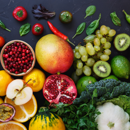 a variety of fruits, vegetables and herbs spread on a dark slate countertop