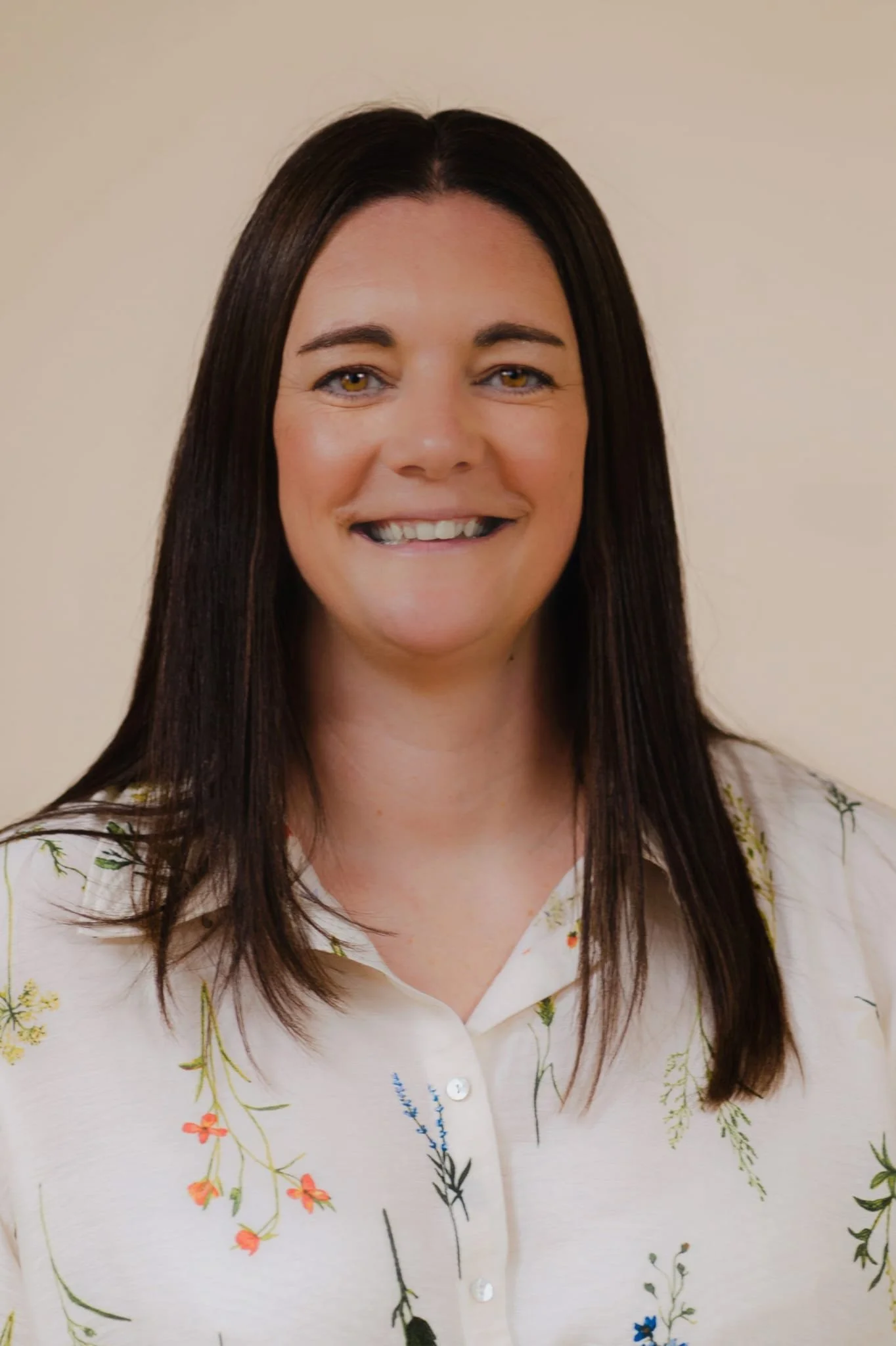 A woman with long dark hair smiles at the camera 