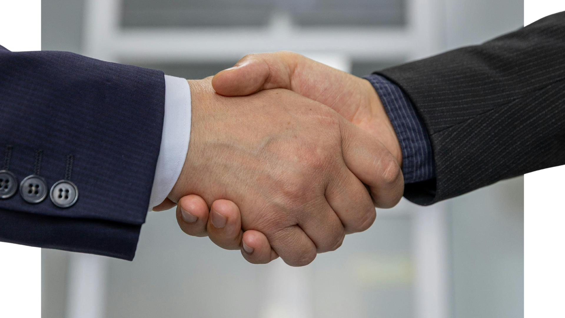 Close-up of two people in business suits shaking hands.