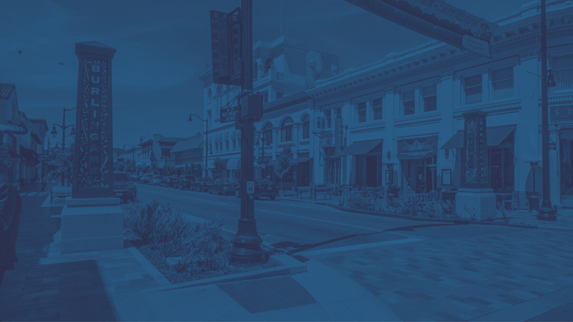 Downtown street scene with parked cars, storefronts, and a prominent sign that reads 'BURLINGAME' on a lamppost.