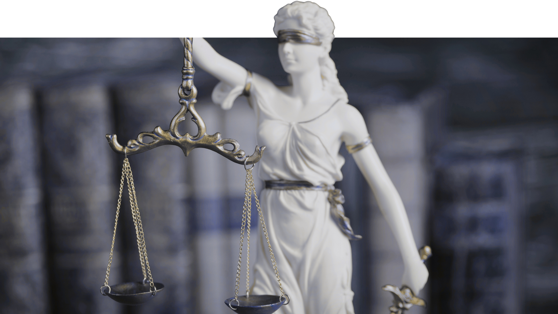 Statue of Lady Justice holding a set of scales, with a background of legal books.
