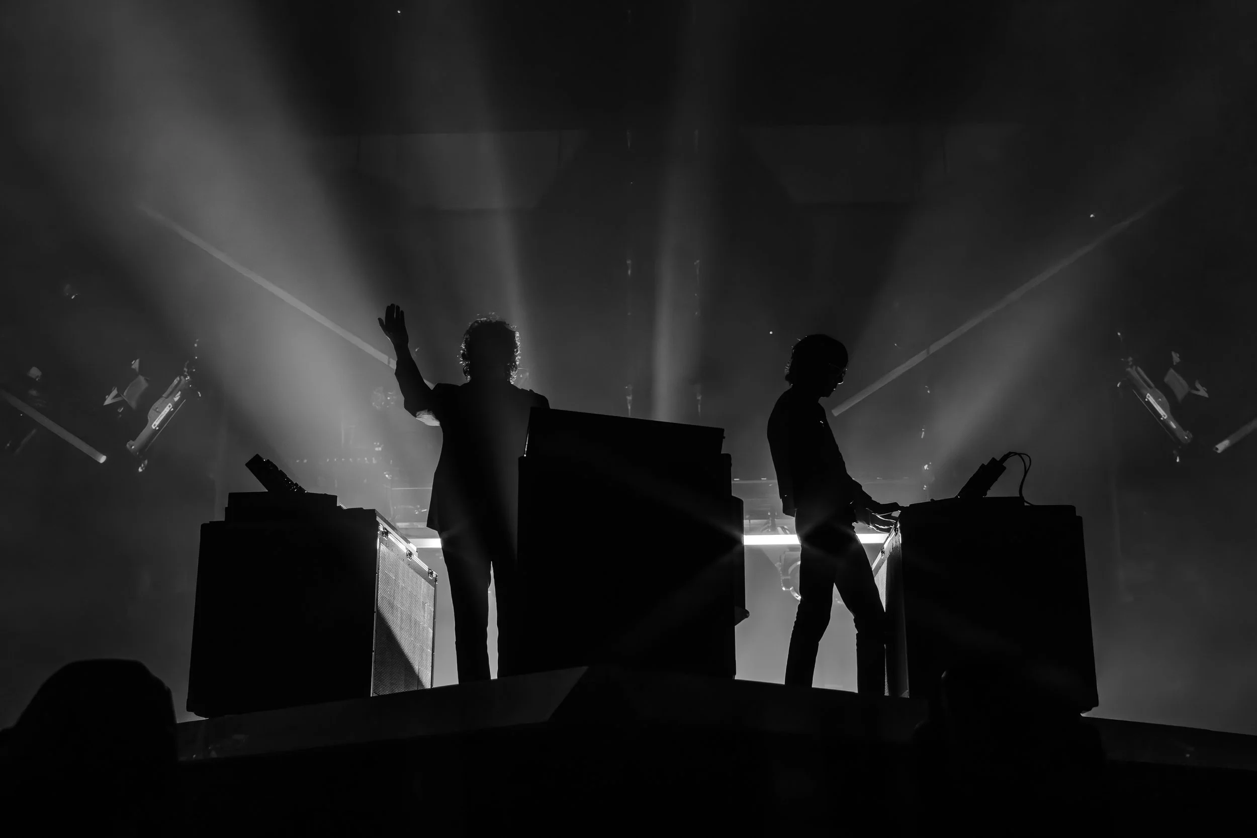 Silhouettes de deux DJ sur scène, avec des équipements de musique, lumière de projecteur, ambiance de concert