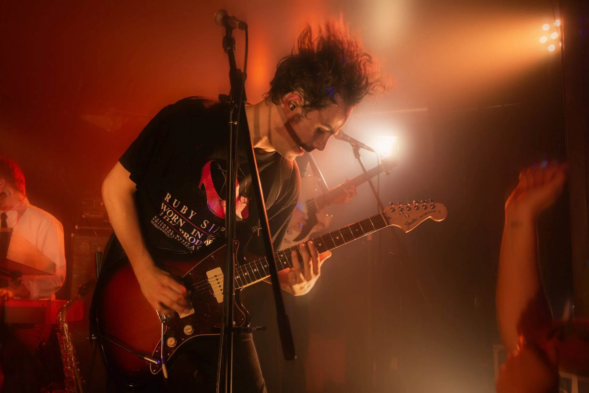 Musicien jouant de la guitare électrique lors d'un concert, éclairage chaud et ambiance festive.