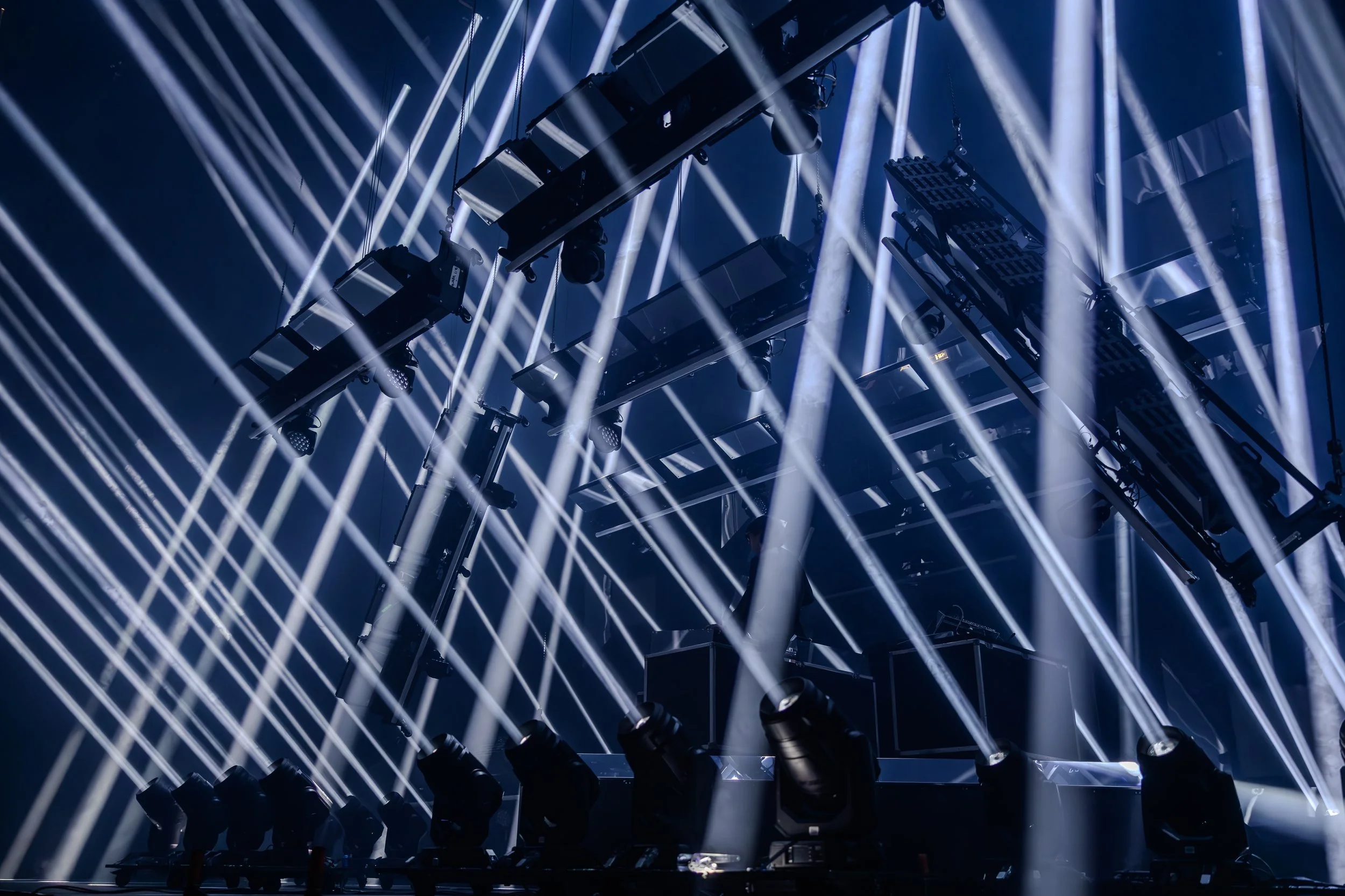 Éclairage de scène avec plusieurs faisceaux lumineux dirigés dans différentes directions sur un fond sombre.