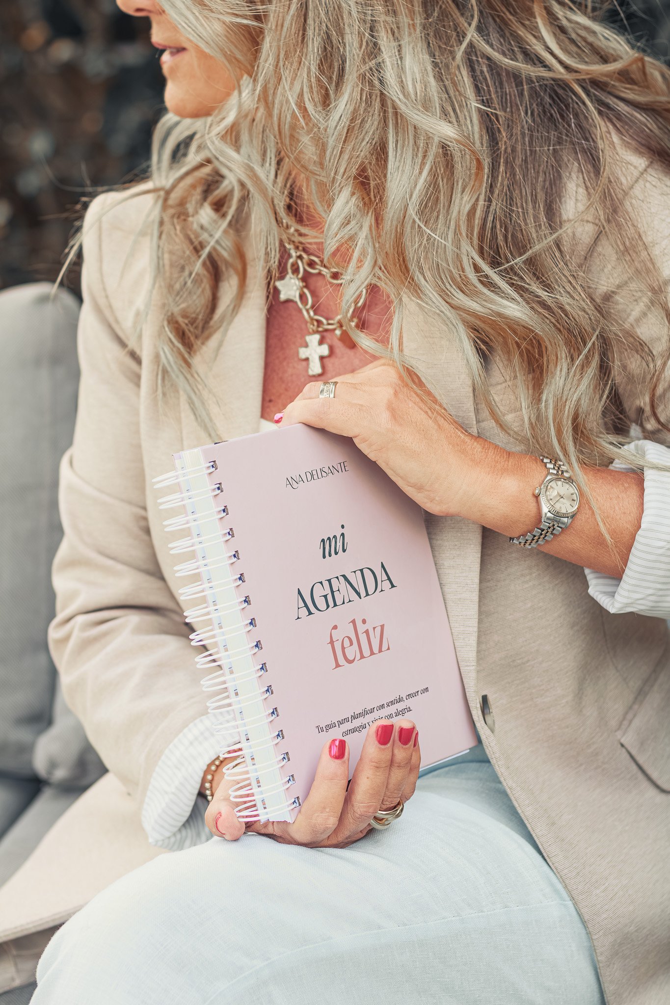 Una mujer sosteniendo una agenda rosada que dice 'Mi agenda feliz'.