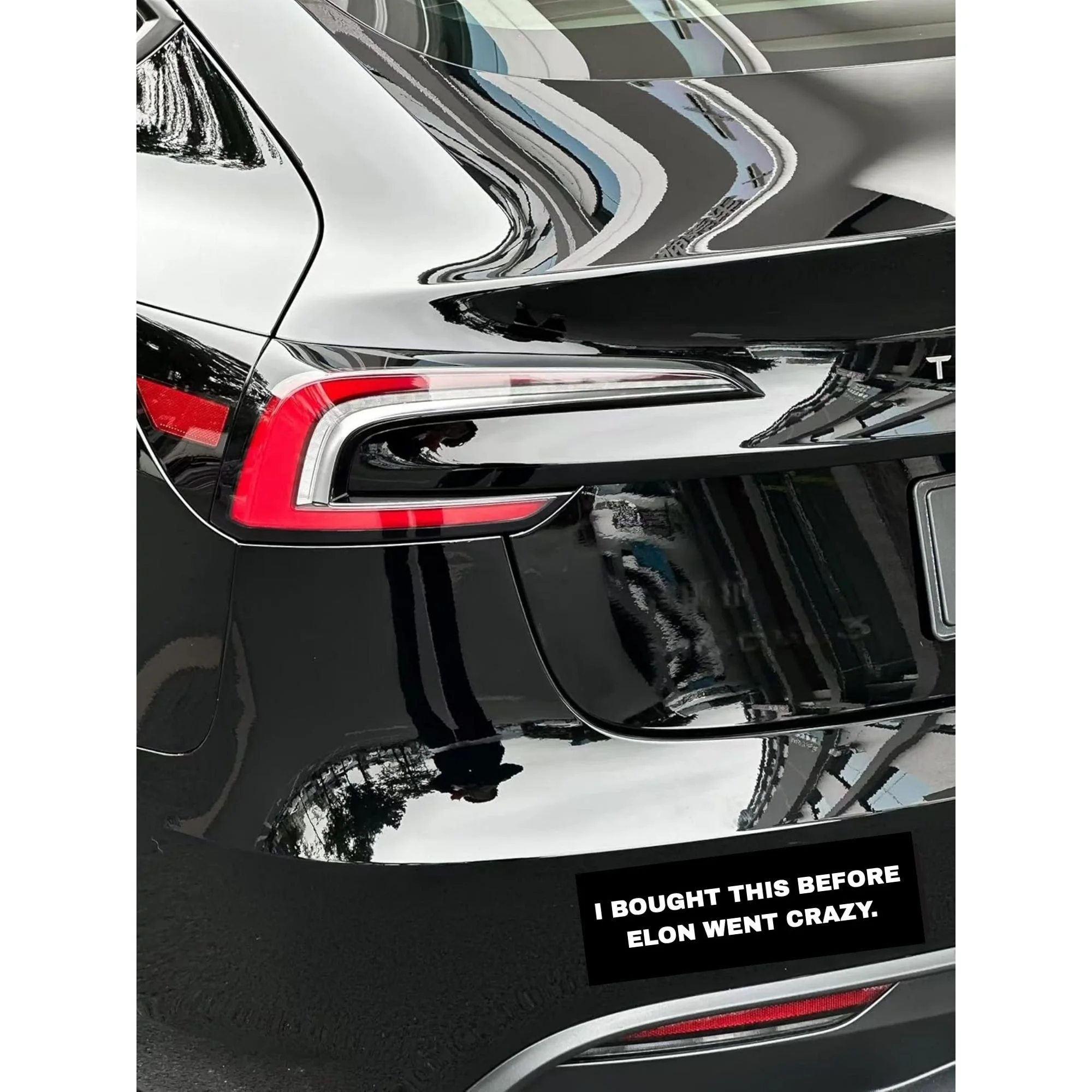 Close-up of the rear section of a black Tesla car, focusing on the taillight and trunk, with a caption that reads, "I BOUGHT THIS BEFORE ELON WENT CRAZY."