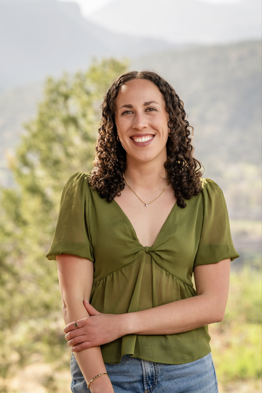 Natalie Youssef, Thrive With You founder, smiling outdoors in a natural mountain setting
