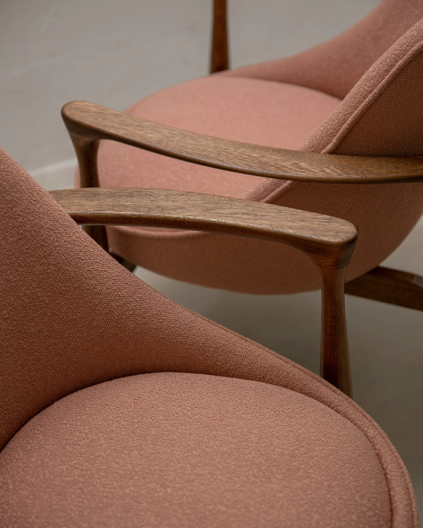 Close-up of three pink upholstered chairs with wooden armrests.