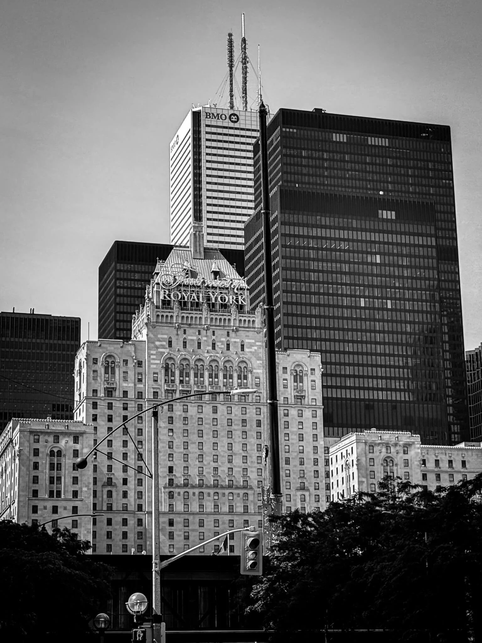 Black and white photo of skyscrapers in New York City, including the Royal York Hotel building in the foreground and taller modern office buildings with antennas in the background.
