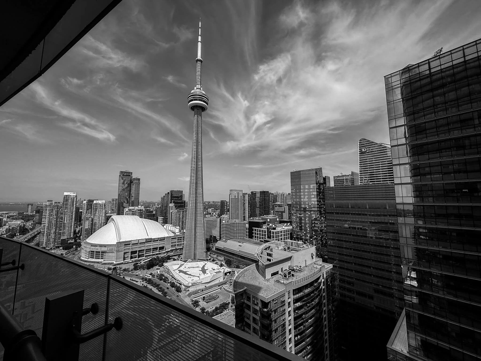 Black and white photo of Toronto skyline featuring CN Tower with surrounding modern high-rise buildings.