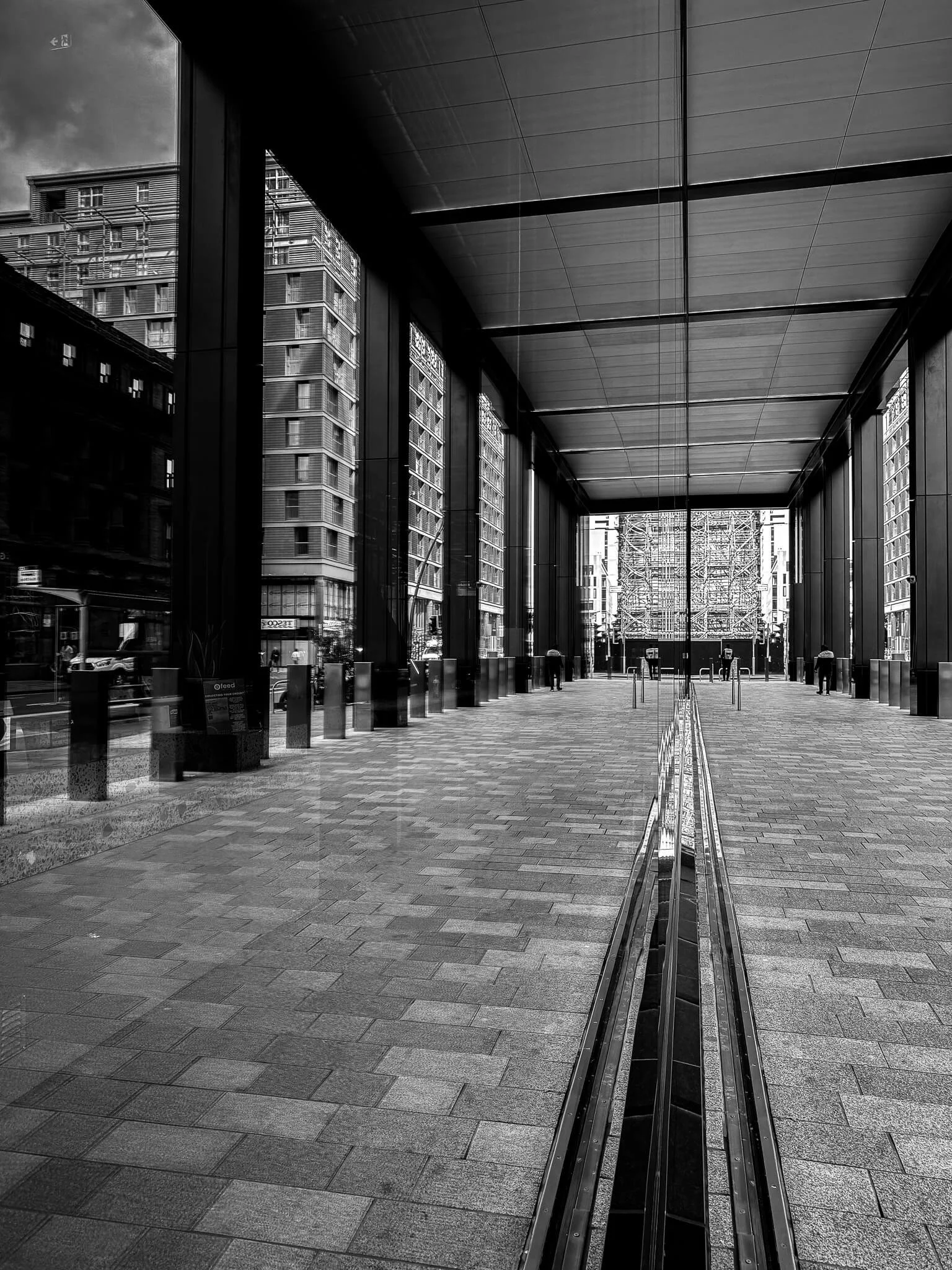 Black and white photo of the entrance to a modern office building with tall glass windows and reflective surfaces in Glasgow