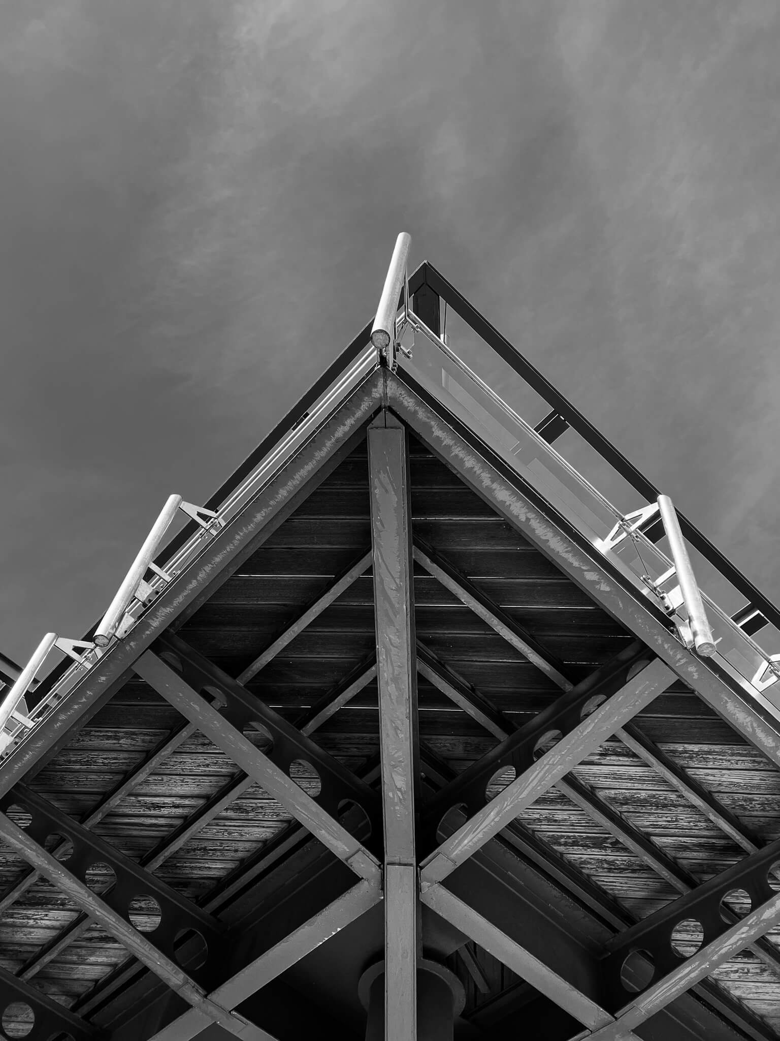 A black and white photo of the underside of a modern building with a steel structure