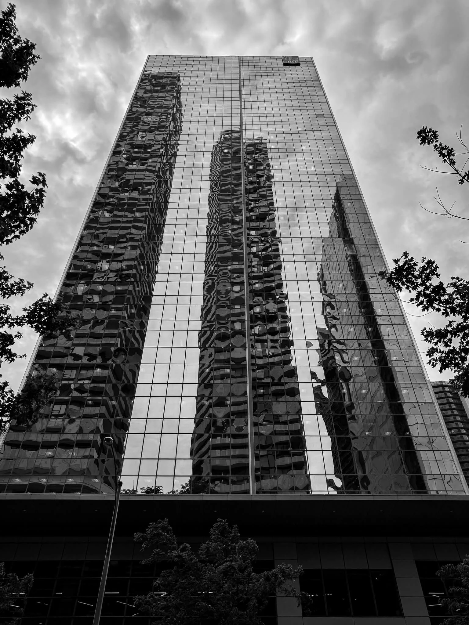 A tall glass skyscraper in Toronto reflects surrounding buildings