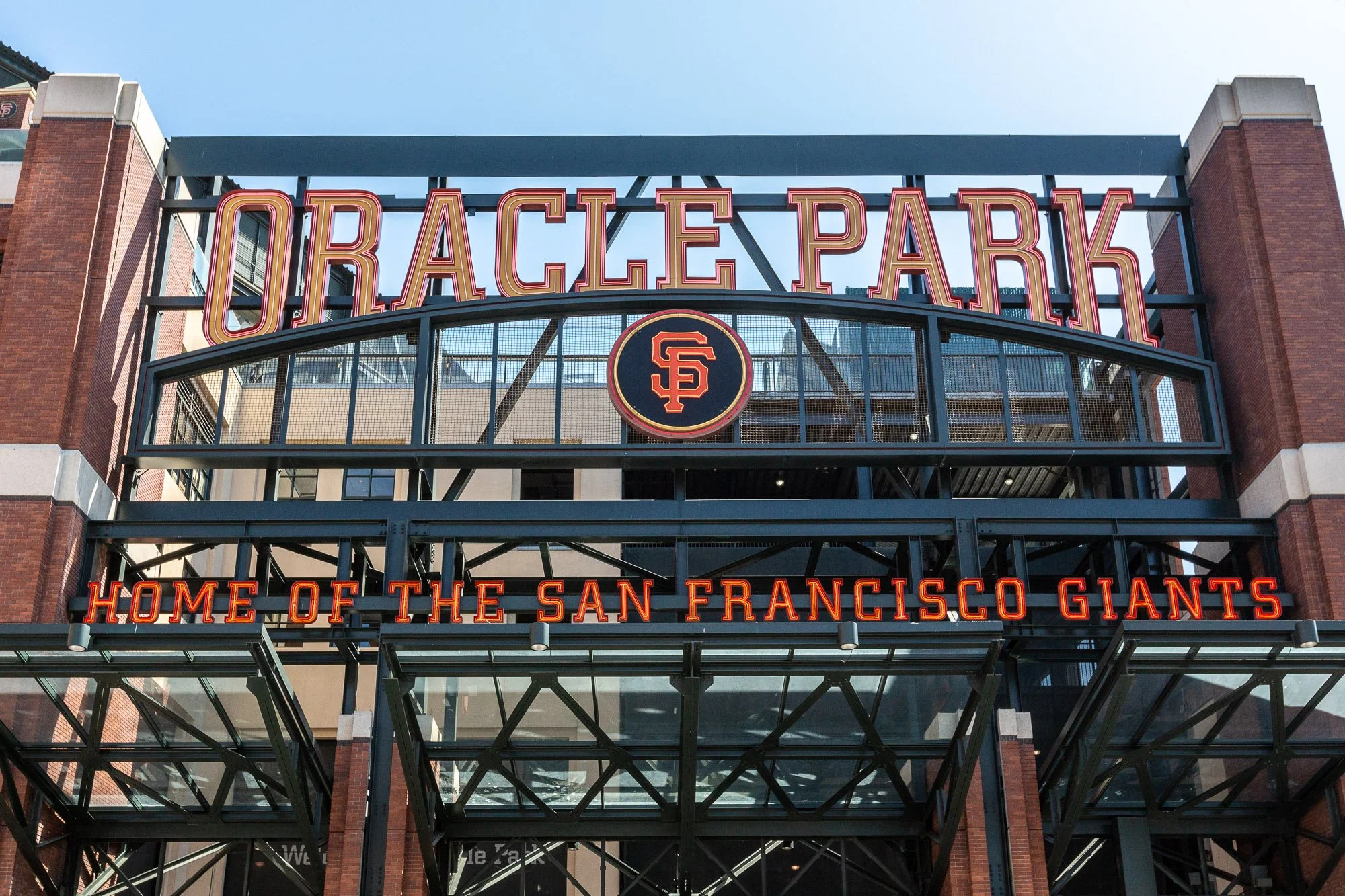 Entrance of Oracle Park stadium with neon signage reading 'Home of the San Francisco Giants' and the SF Giants logo.