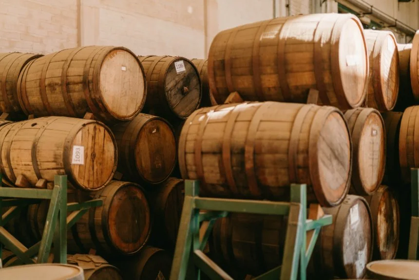 Stacked wooden aging barrels on green metal racks