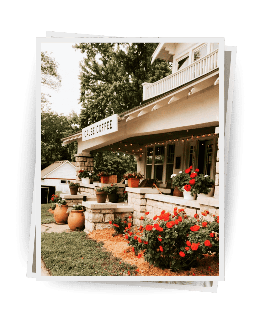 A cozy coffee shop named Cause Coffee in the DYM Building, with flower pots and red flowers on a stone porch.
