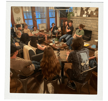 College students and young adults gathered in a cozy living room for a community discussion around faith and life.