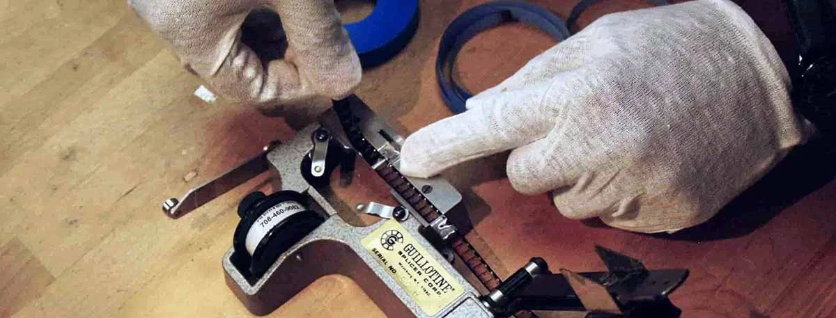 Person wearing gloves adjusting a circular measuring instrument on a wooden table.