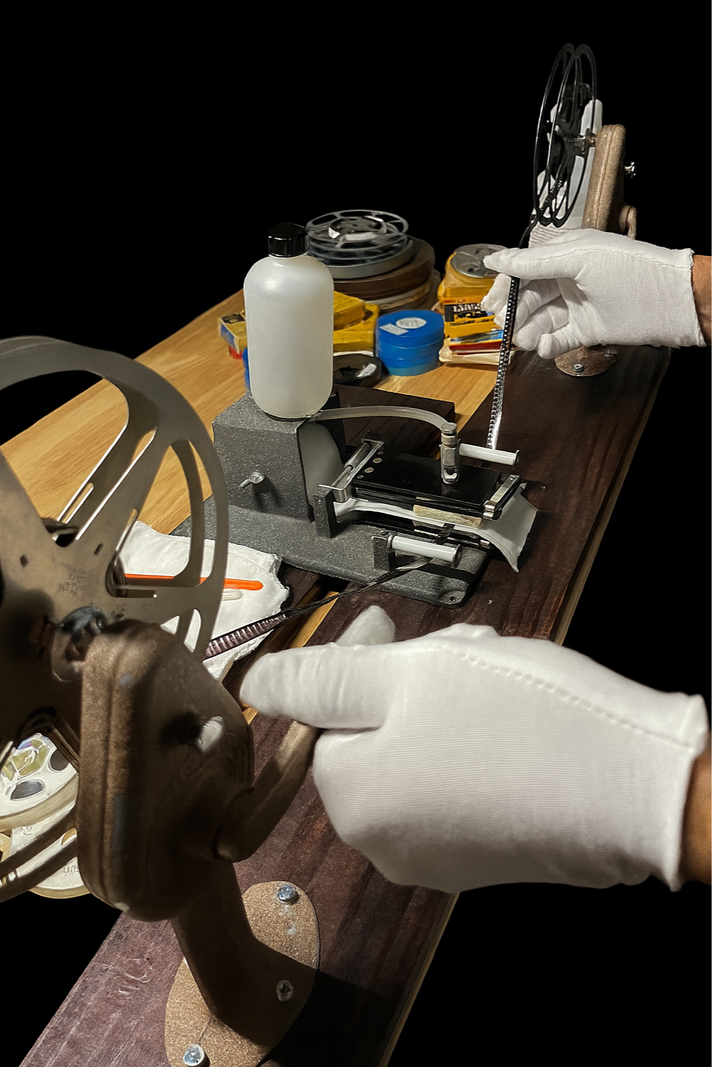 Person wearing white gloves handling film in a film developing machine.