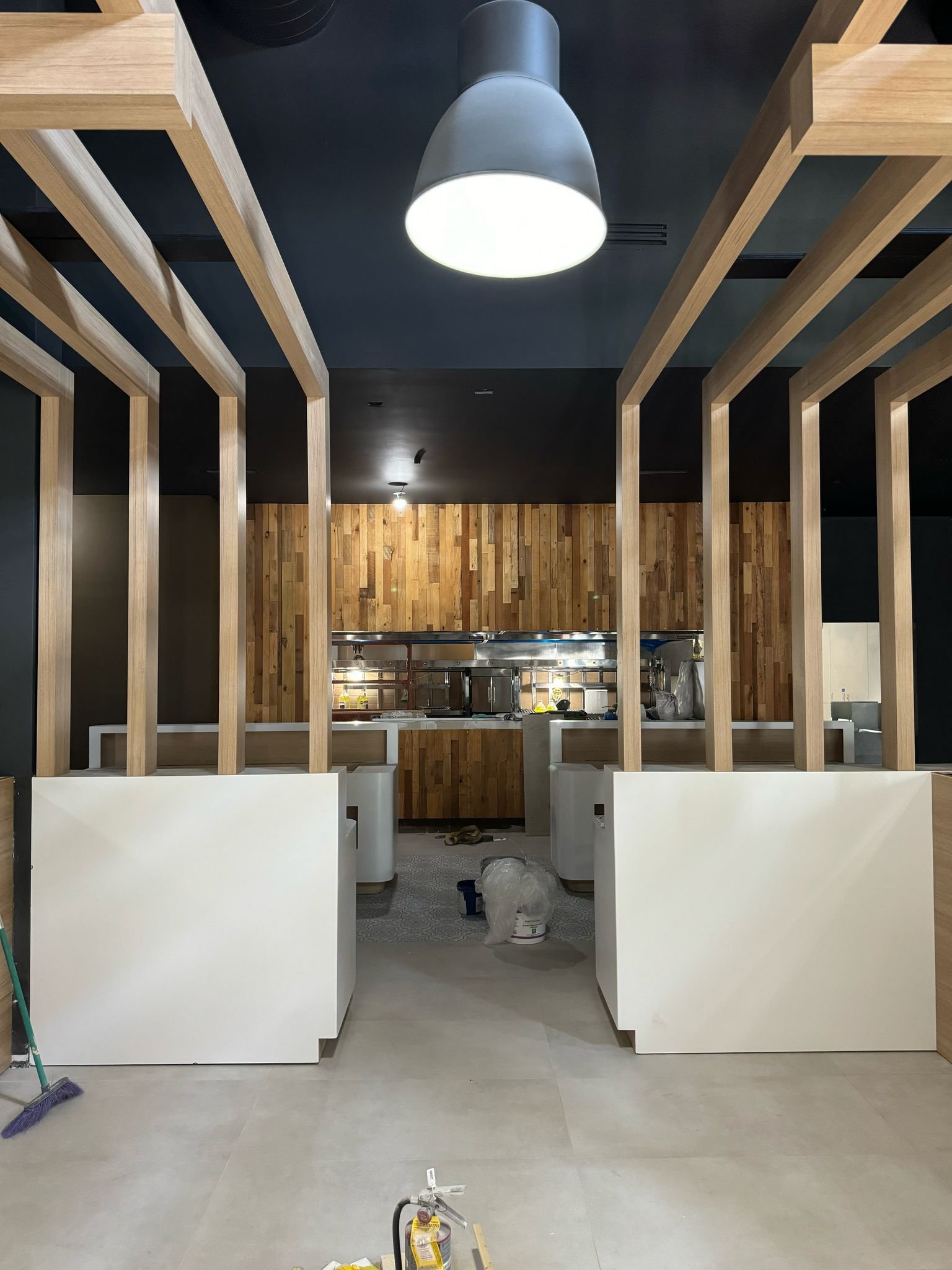 Interior of a building under construction with wooden frames, a black ceiling, and construction tools on the floor.