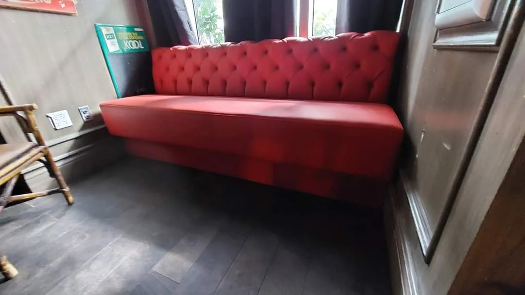 Red upholstered couch with tufted backrest in a cozy room.