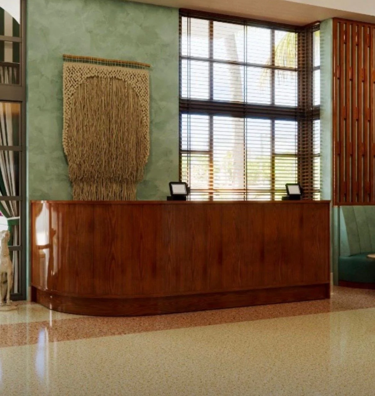 A hotel or reception desk with a wooden counter, two small black-frame signs, and large windows with wooden blinds in the background. There is green wall decor and a wooden partition on the right side.