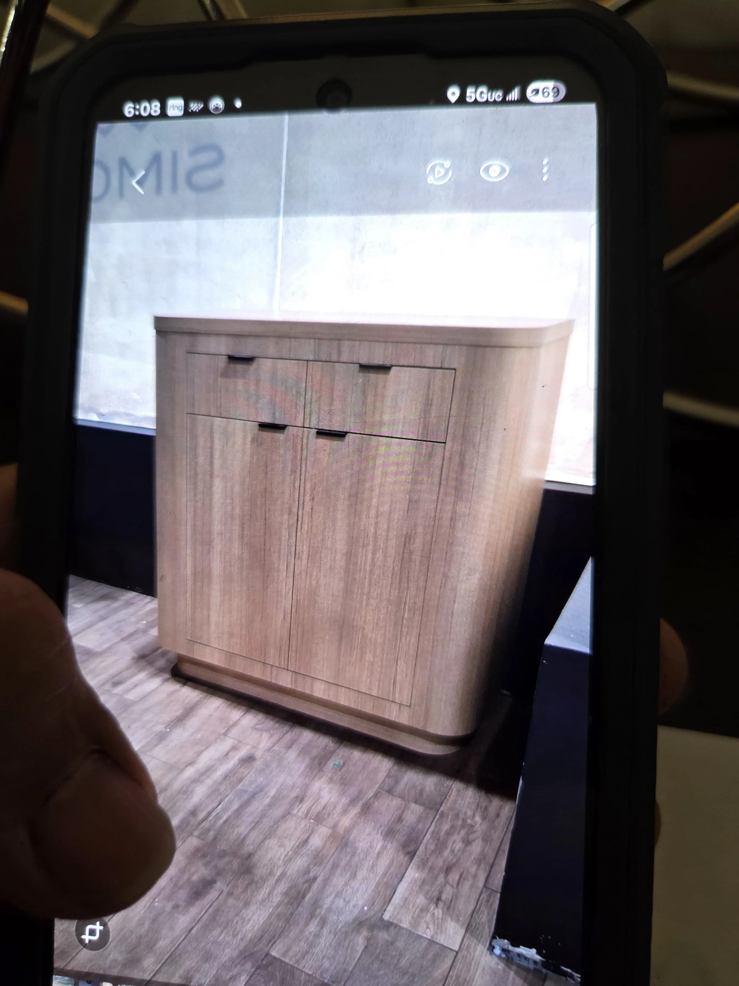 A floor with wooden planks, partially covered by a piece of furniture that looks like a wooden cabinet or dresser with drawers. The furniture appears to be new or well-maintained.