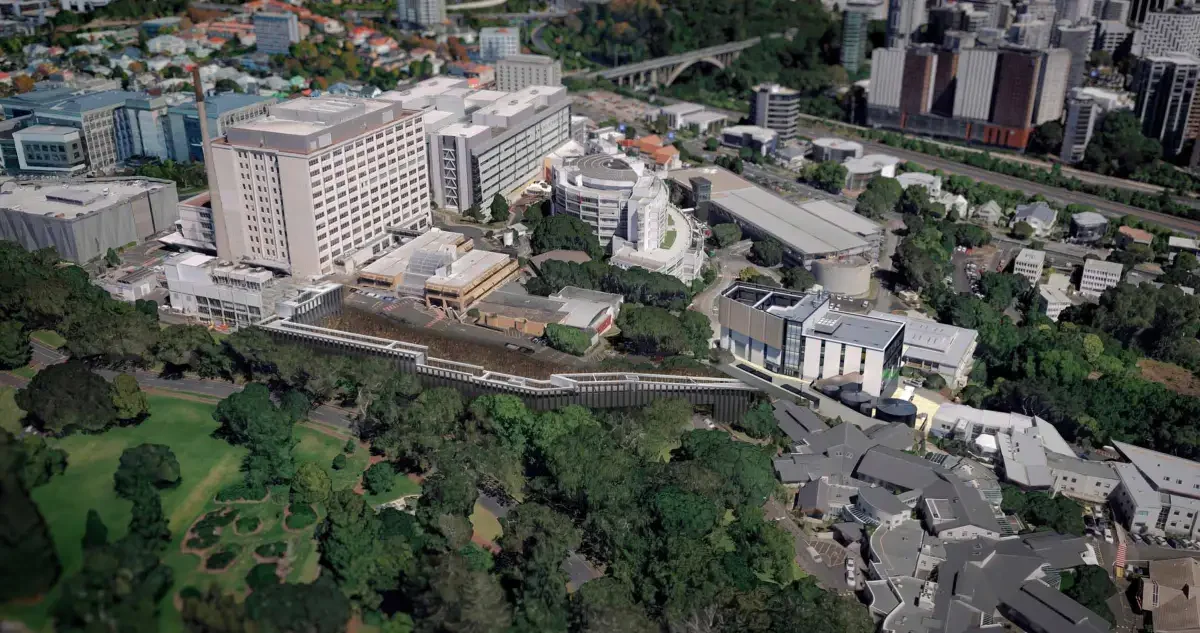 Aerial view of a cityscape with a large hospital complex, green parks, and surrounding urban buildings.
