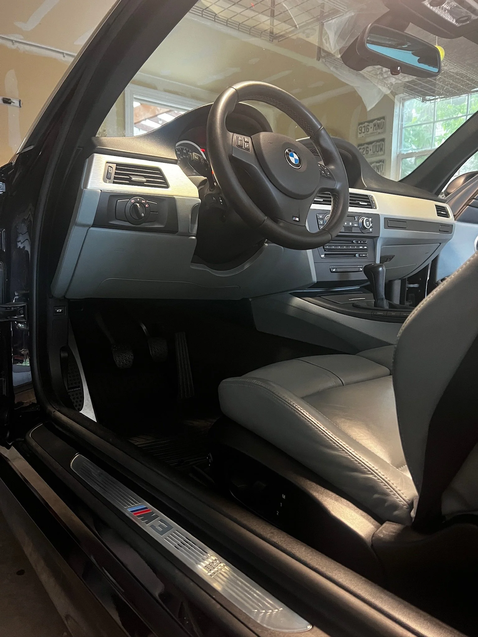 Interior of a BMW car, showing the steering wheel, dashboard, gear shifter, and driver seat.
