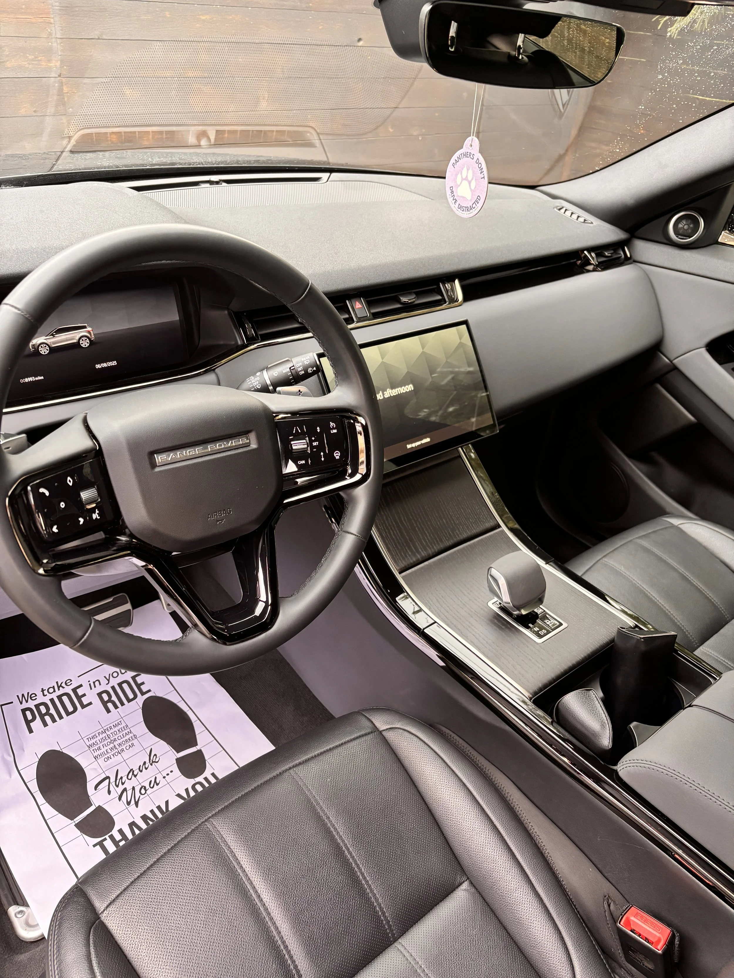 Interior of a Range Rover vehicle showing the steering wheel, center console, and dashboard with a digital display screen.