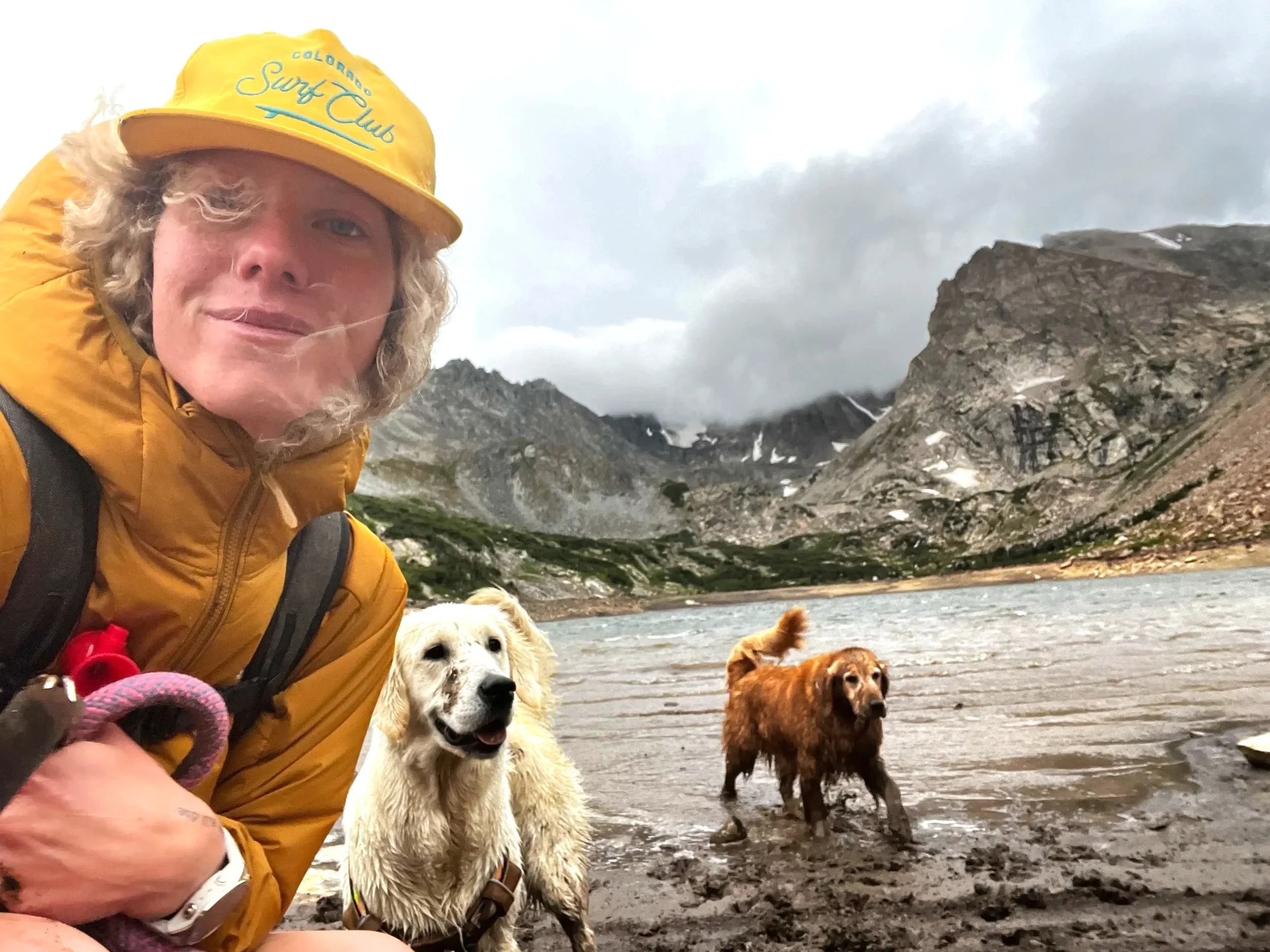 Therapist  sitting with two dogs by a Colorado mountain lake, representing nature and animal-assisted therapy