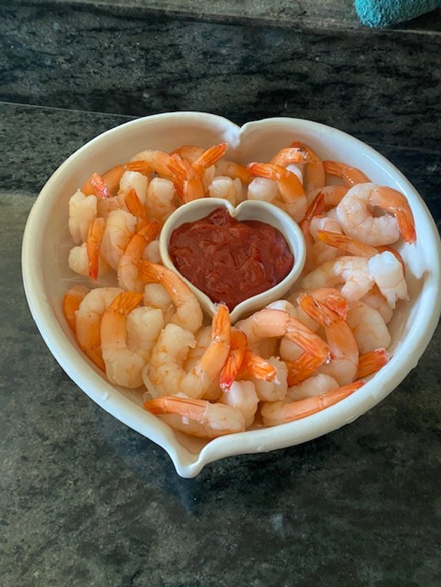 Shrimp with cocktail sauce in a heart-shaped bowl.