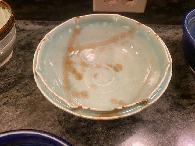 Empty ceramic bowl with leftover sauce on a dark countertop.