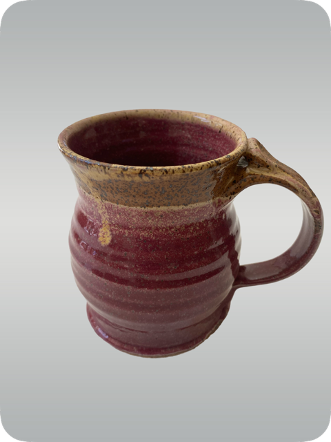 A ceramic mug with a red and brown glaze, slightly textured surface, and an ergonomic handle.