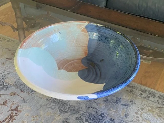 Colorful ceramic bowl with abstract multicolored design on a patterned rug.