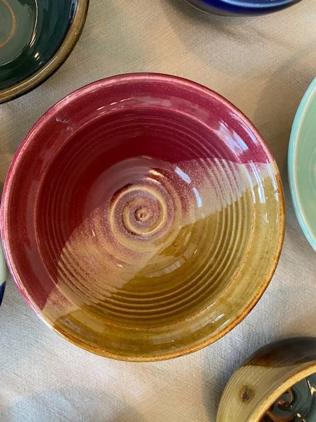 Colorful ceramic bowl with a red and yellow gradient and spiral design, viewed from above.