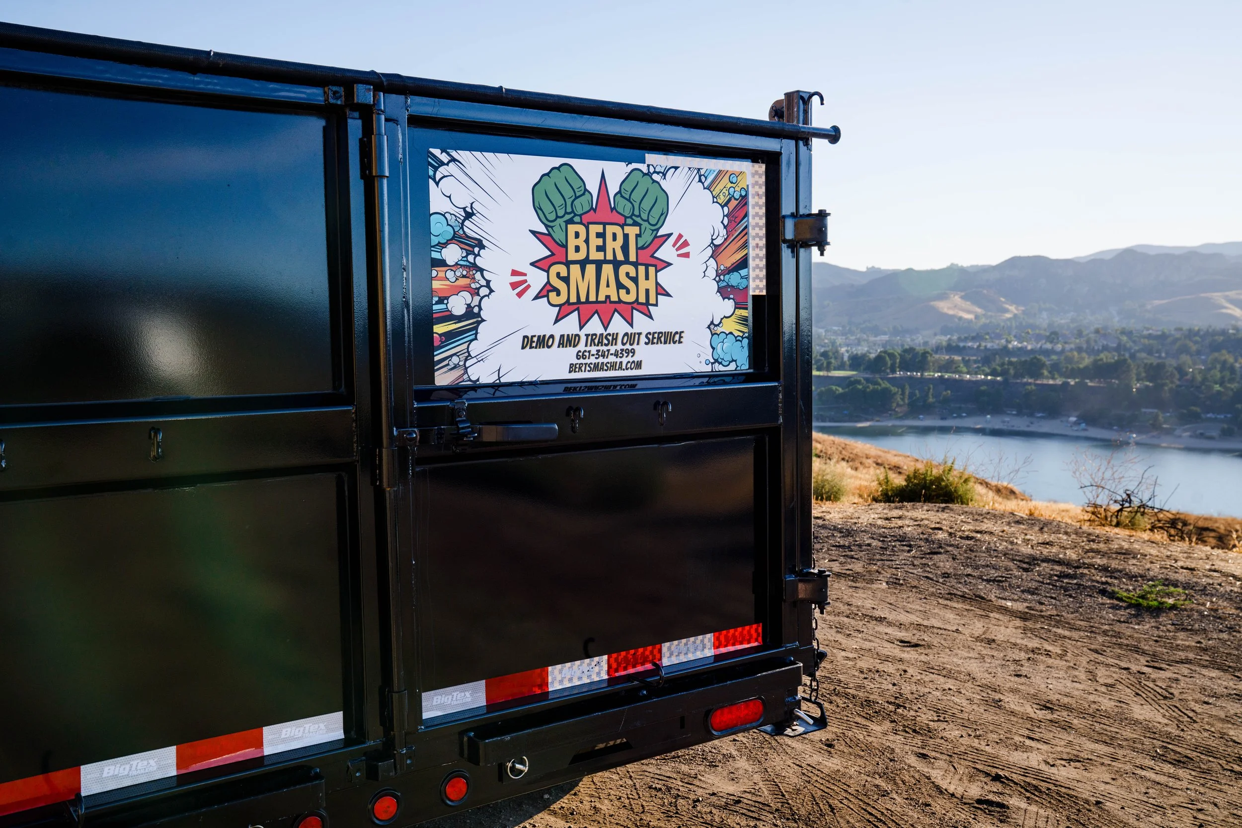 Back of a black truck trailer with the view of a lake in the background.
