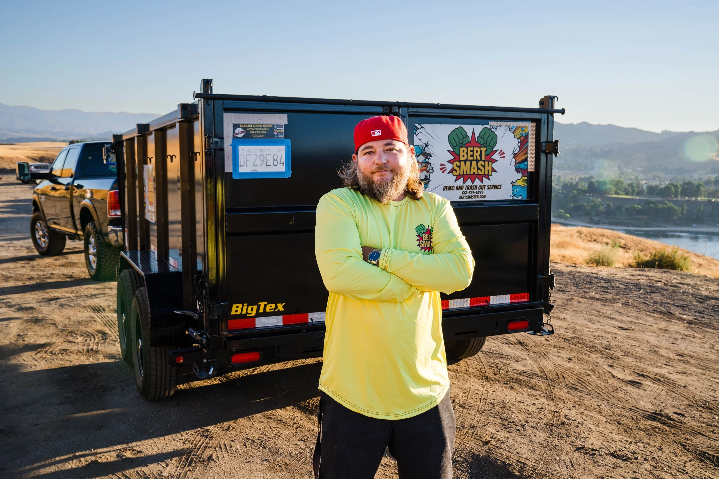 Owner of waste disposal services in Santa Clarita posing next to his black trailer.