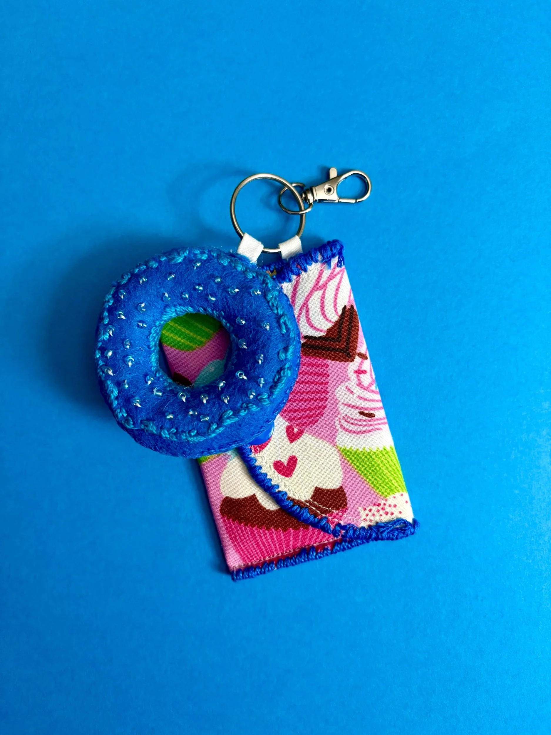 Keychain with a plush blue donut and a fabric cake slice on a blue background.