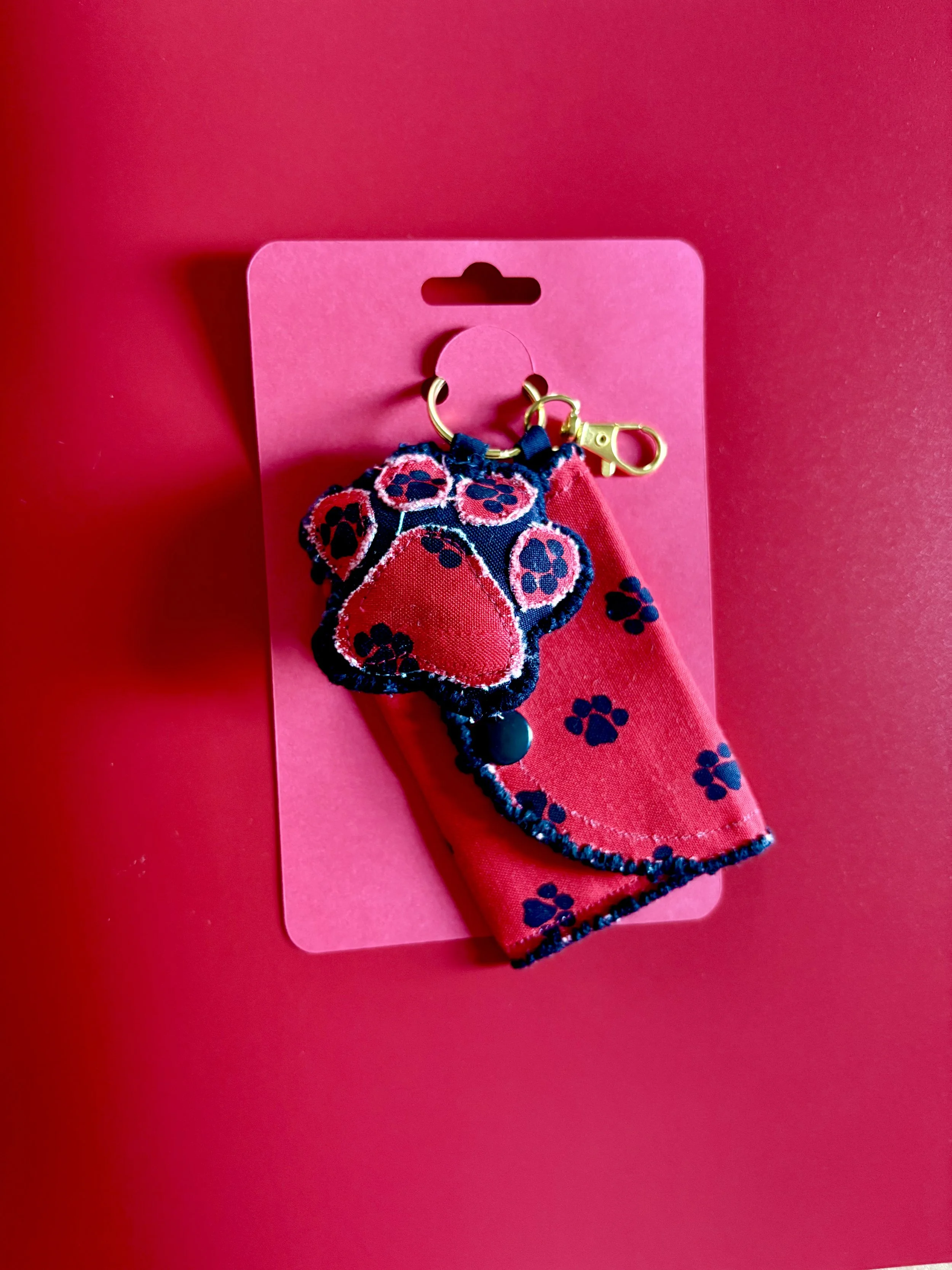 Pink card with a leash featuring a paw print pattern, including a pink paw-shaped embroidered patch and a matching fabric piece with paw prints.