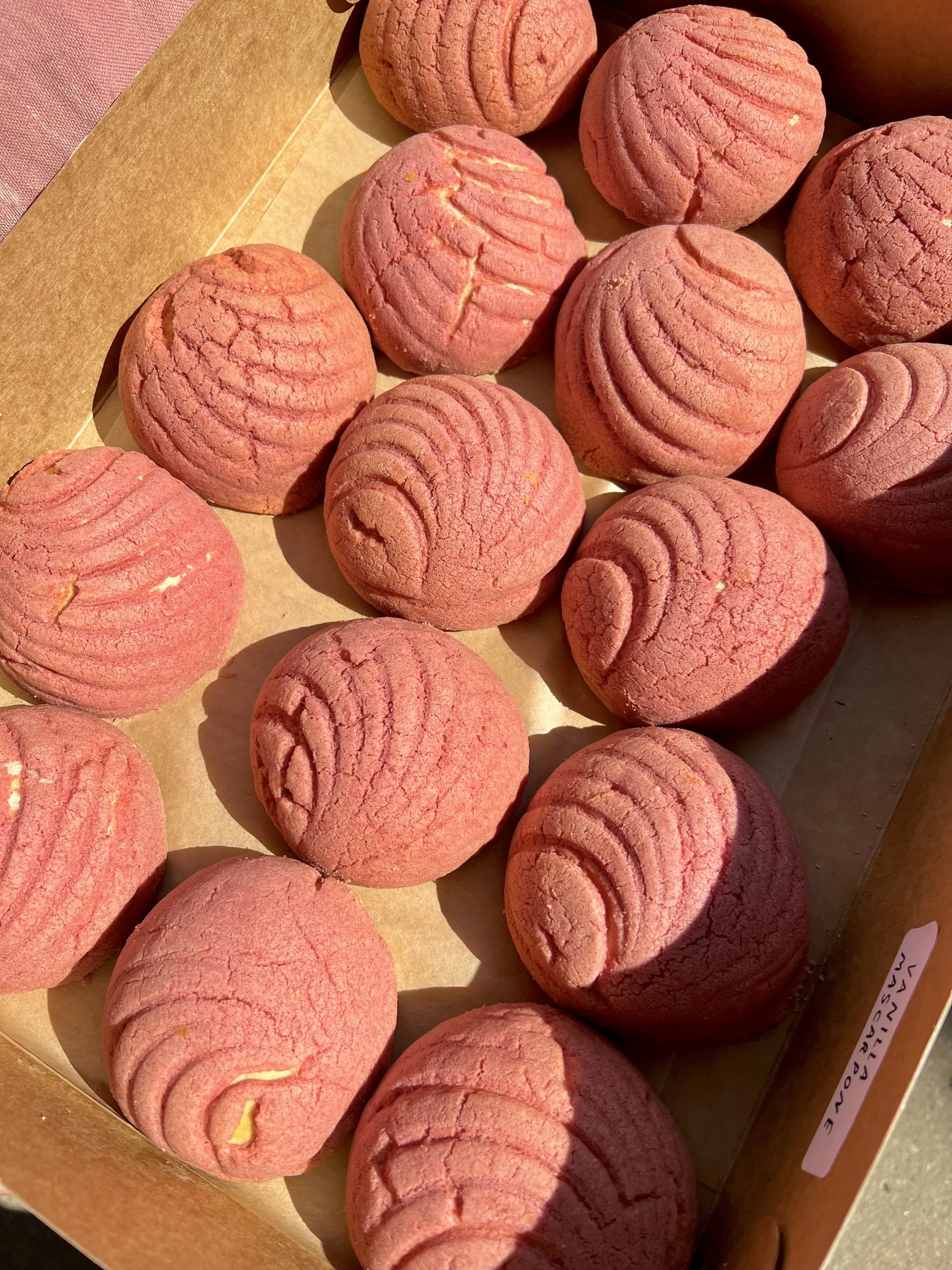 A tray of pink salted caramel cookies with ridged, swirl designs, some showing a cracked surface.