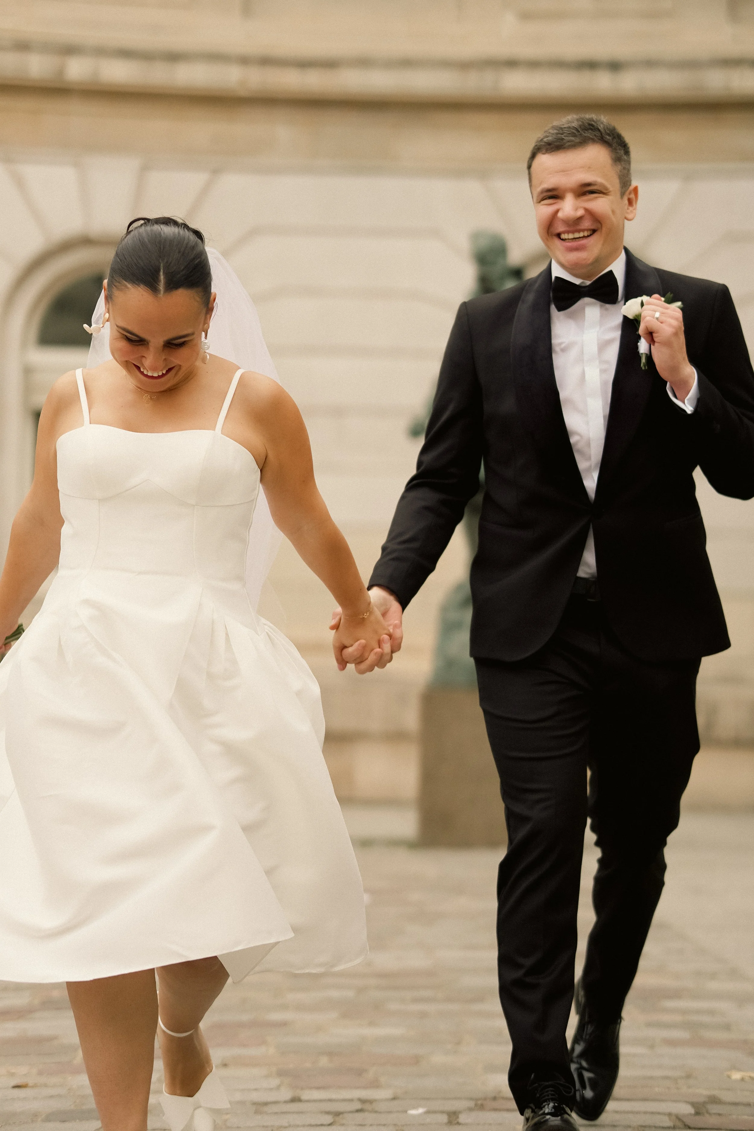 A joyful bride and groom holding hands and walking together indoors at their wedding celebration.