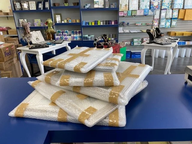 Stacked wrapped packages on a blue table in a craft store.