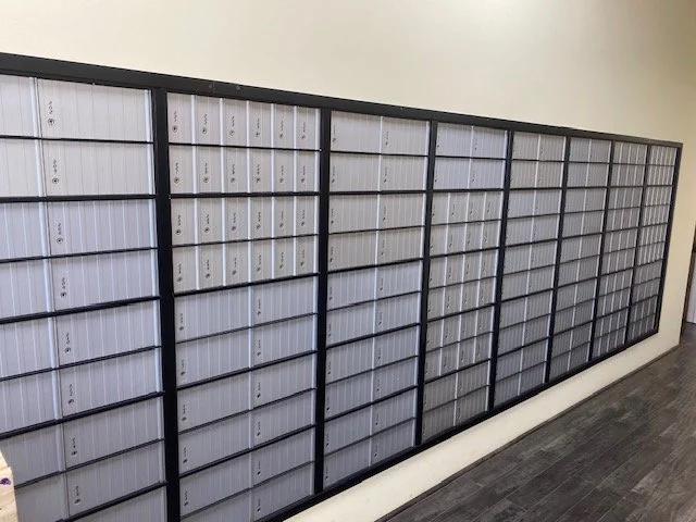 Row of unlocked gray mailboxes in an indoor setting