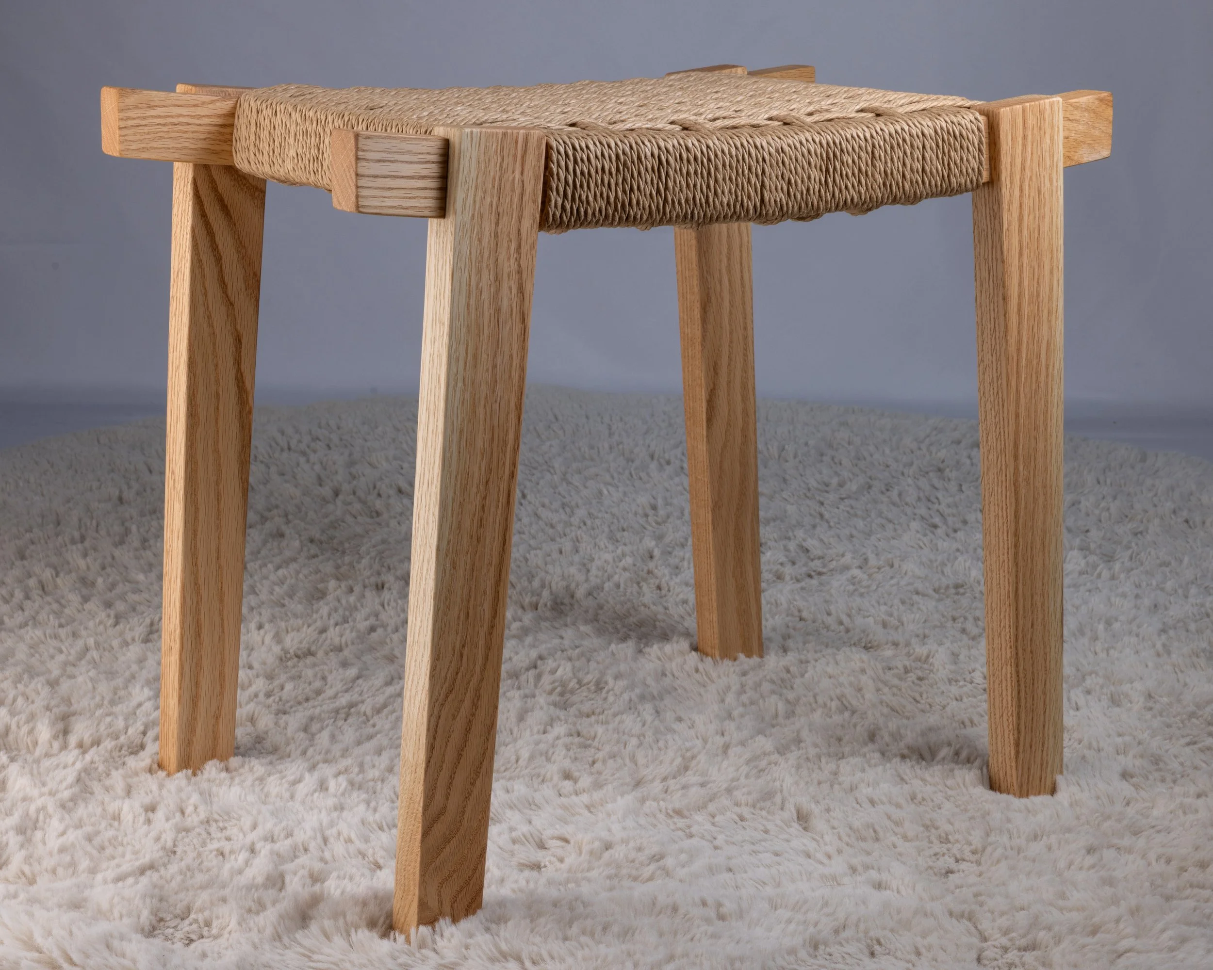 Wooden stool with woven rope seat.